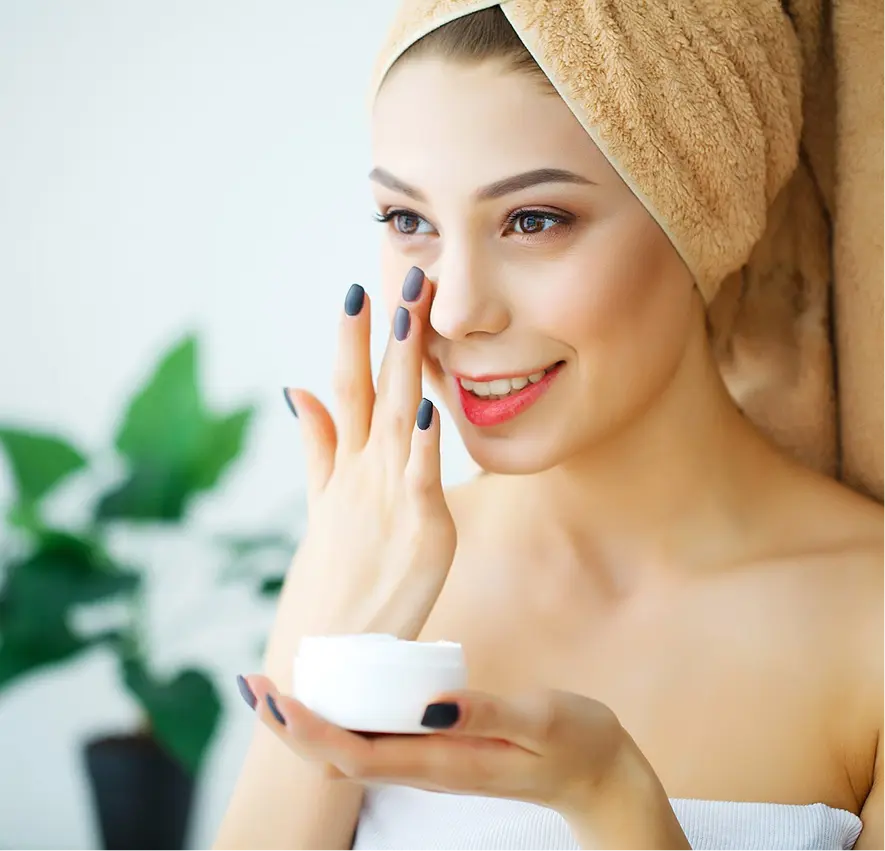 Smiling woman applying moisturizer, towel wrapped
