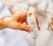 Hand holding moisturizer bottle, cream on hand