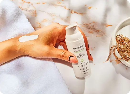 Hand holding moisturizer bottle, cream on hand